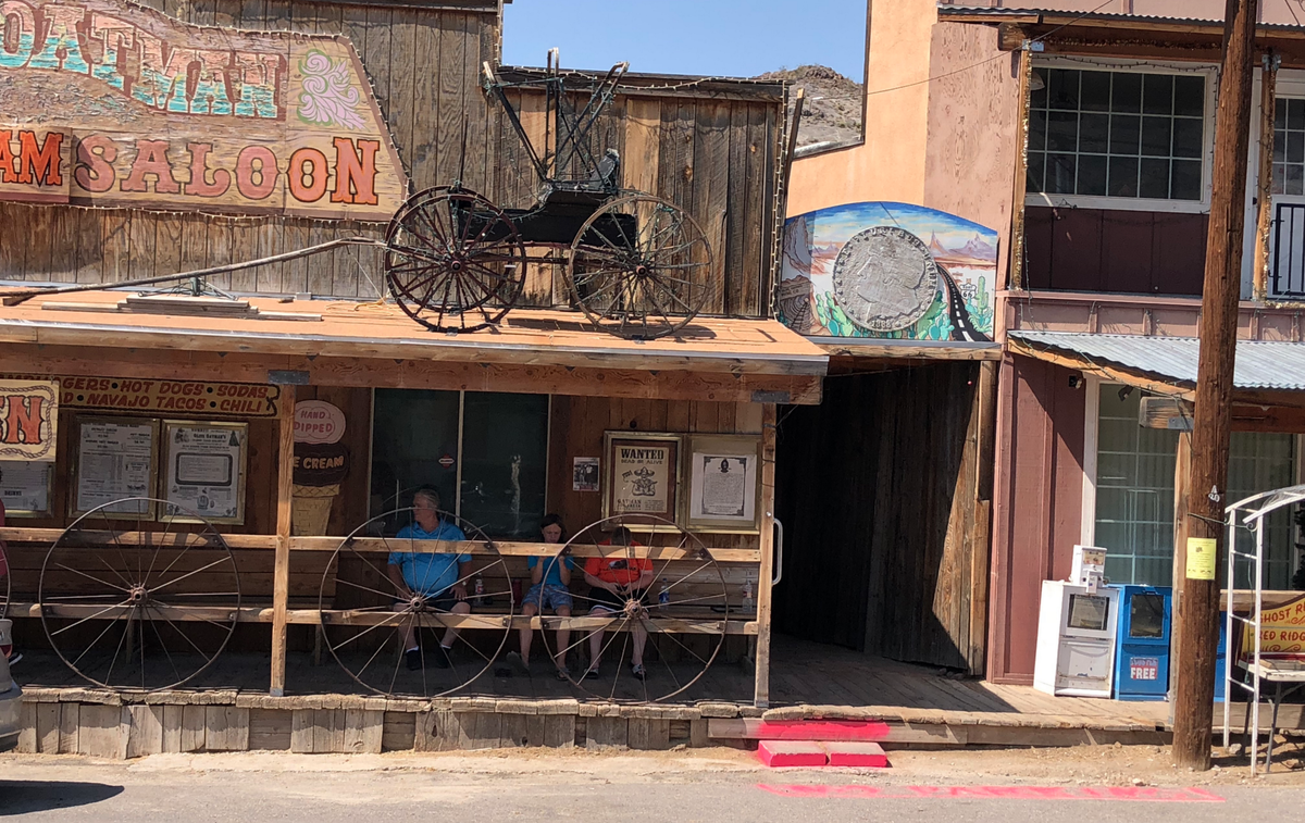 Old wooden saloon front in Oatman with a buggy on the roof and wagon wheels along the porch
