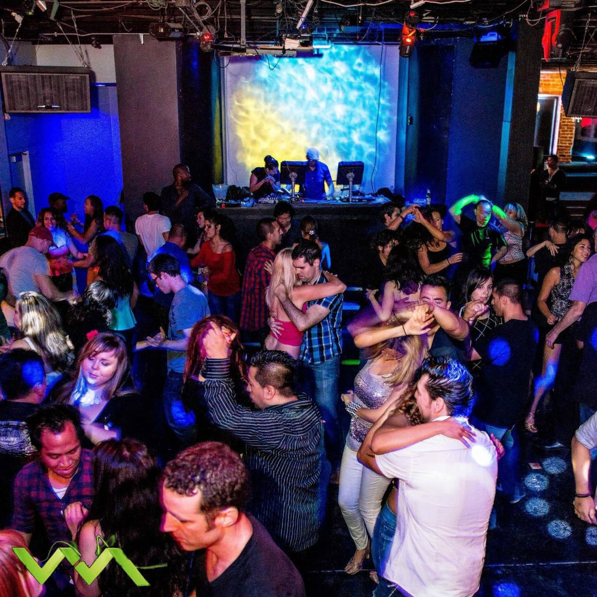 Crowded dance floor of couples dancing under blue nightclub lights