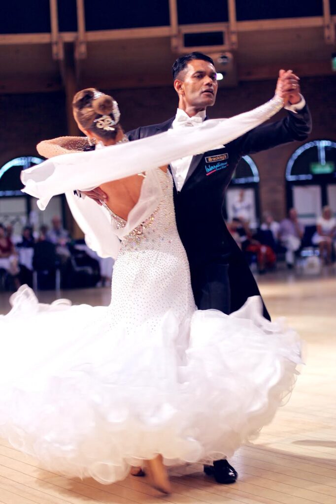 Ballroom couple dancing, the woman in a white feathered gown with floating sleeves, the man in tails