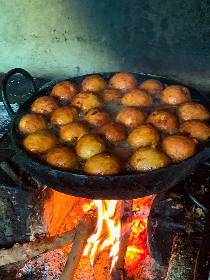 Vadas frying in oil in a blackened wok over a wood fire